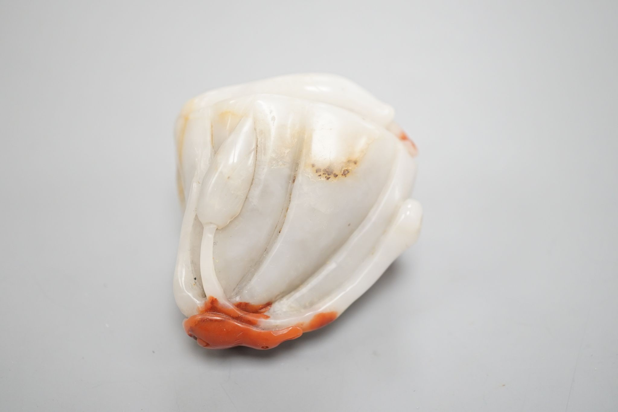 A Chinese pale celadon and russet jade 'lotus pod and fish' carving 6cm
